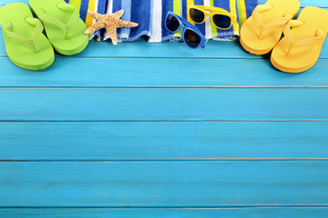 Summer beach background border with sunbathing towel sunglasses and accessories on old blue wood...