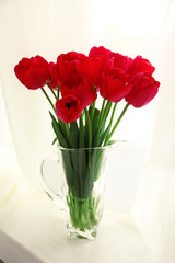 Bouquet of fresh tulips on windowsill background