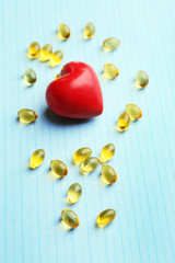 Red heart and cod liver oil, on blue background