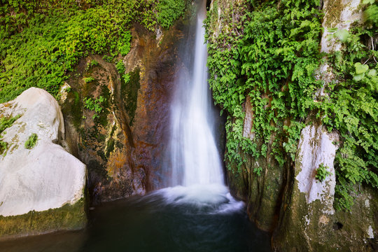  Waterfall in rocky grot at mountains