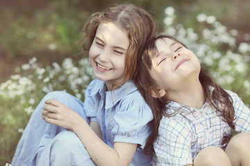 Two cute girls laughing on a beautiful summer meadow
