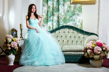The girl in azure dress sitting on the couch