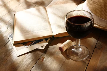 Papier Peint photo Vin verre de vin rouge et vieux livre ouvert sur table en bois au coucher du soleil