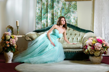 The girl in azure dress lies on a sofa