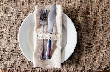 Empty dish, knife and fork on a napkin of burlap