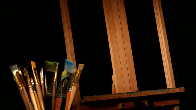 Illustration with easel paints and brushes on black background