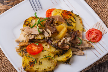 Potato gratin with fresh tomatoes on a white plate