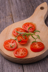Tomato slices with rosemary on a kitchen board