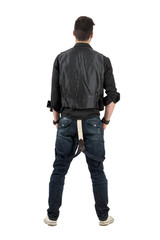 Fototapeta premium Rear back view of young stylish man looking at blank wall