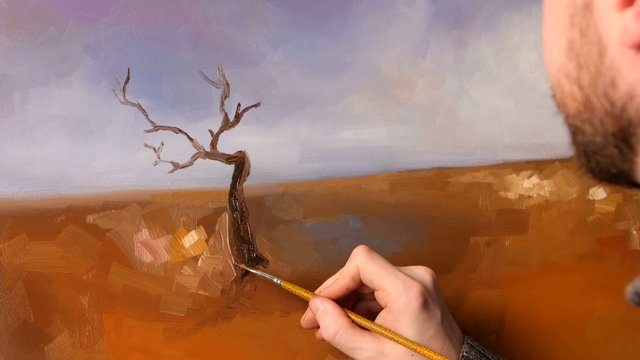 Artist paints a picture of oil paint brush with palette in his