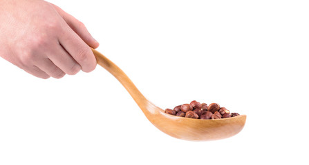 Wooden spoon with nuts in hand.