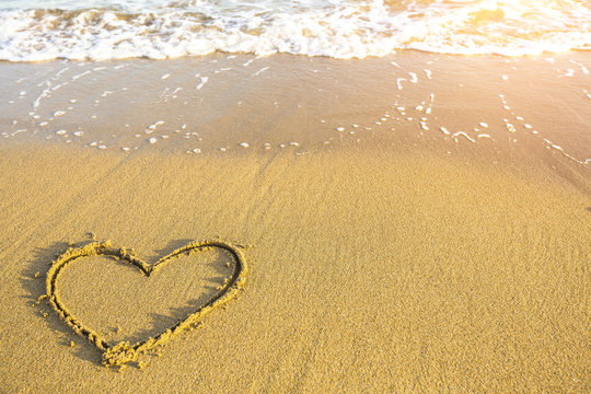 Heart drawn on the sand of ocean beach.