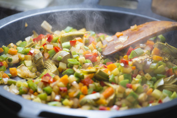Wood spoon mixing veggies on a pan