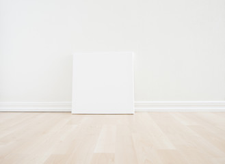Empty room interior with blank canvas on floor