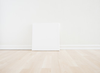 Empty room interior with blank canvas on floor