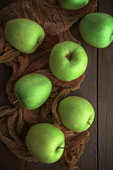 Green apples on wooden table with fabric, top view