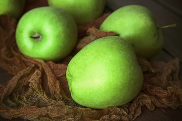 Green apples on wooden table with fabric, closeup