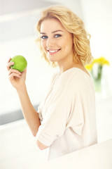 Young woman eating apple in the kitchen