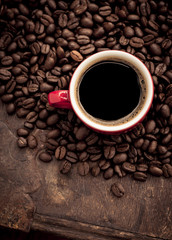 Red cup filled with hot coffee on top of roasted coffee beans