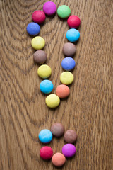 exclamation mark made of coloful praline on wooden background