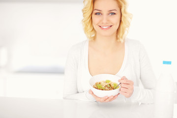 Young woman eating cereal in the kitchen