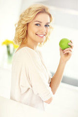 Young woman eating apple in the kitchen