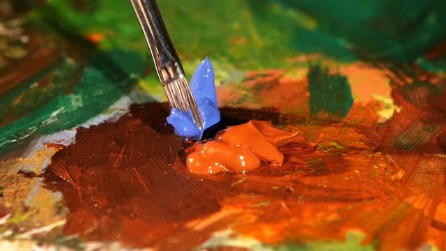 Painter mix brown, blue and orange colors oil painting on