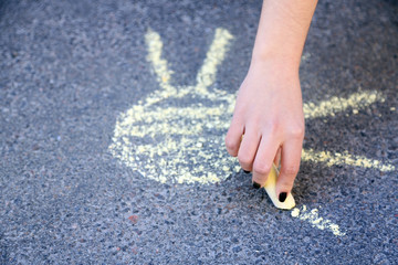 Girl drawing with chalk on asphalt