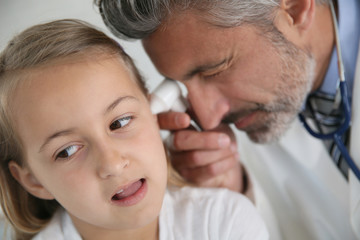 Doctor examining girl's ear