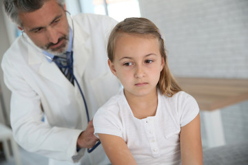 Obraz na płótnie Canvas Doctor examining young girl with stethoscope
