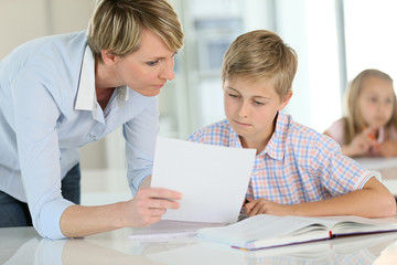 Teacher showing paper to pupil in class