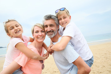 Parents giving piggyback ride to children at the beach
