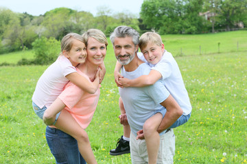 Fototapeta premium Parents giving piggyback ride to kids in countryside