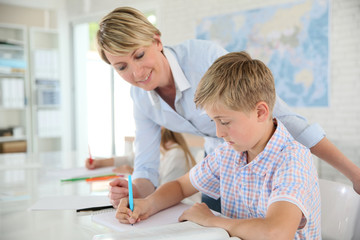 Teacher helping pupil with writing in class