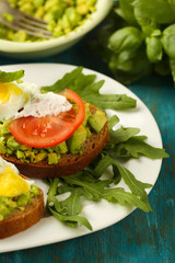 Tasty sandwiches with egg, avocado and vegetables on plate, on wooden background