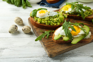 Tasty sandwiches with egg, avocado and vegetables on wooden background