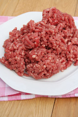 carne macinata cruda su piatto su tavolo di legno