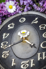 Clock surrounded by spring flowers with a ring in the middle.