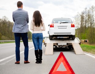 Couple near tow-truck picking up broken car