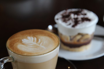 Hot cappuccino in glass cup on wooden table.