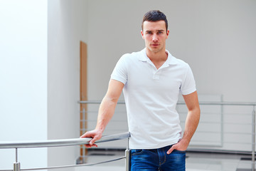 Man in a polo shirt stands leaning on railing