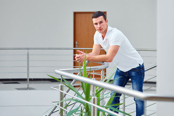 Man in a polo shirt stands leaning on railing