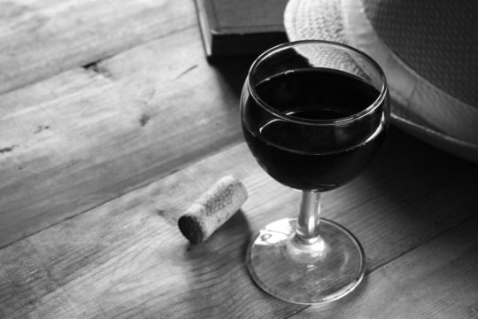 red wine glass and old book on wooden table. vintage filtered