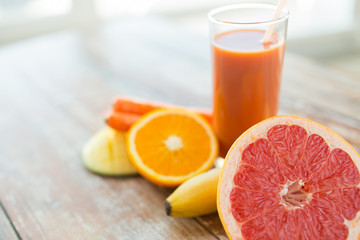 close up of fresh juice glass and fruits on table