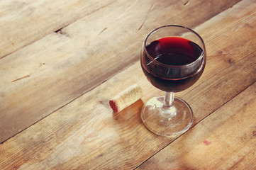 Red wine glass and old book on wooden table at sunset burst
