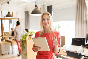 woman with tablet pc showing thumbs up at office