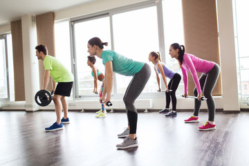 group of people exercising with barbell in gym