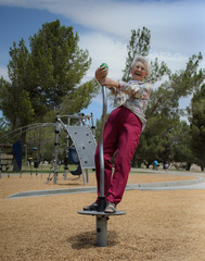 Happy elderly women playing in park on park toys