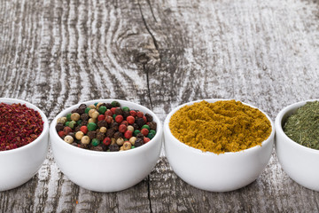 White ceramic cups with different kinds of spices on old wooden