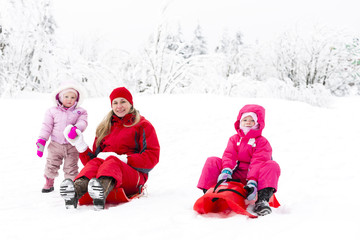 Fototapeta na wymiar mother and her little daughters with bobs in snow